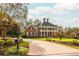 Stately brick home with a grand entrance, mature landscaping, and a circular driveway provides curb appeal at 1100 Muirfield Ct, Alpharetta, GA 30005
