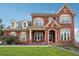 Two-story brick home featuring dormer windows and a covered front porch with manicured lawn at 2220 Stirling Bridge Rd, Cumming, GA 30041