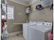 A well-equipped laundry room complete with a washer, dryer, storage shelf, and ironing board at 115 Dorys Way, Dallas, GA 30157