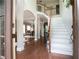 Open foyer featuring hardwood floors, white staircase, and an arched doorway leading to the dining room at 507 Autumn Walk, Canton, GA 30114