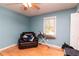 Bedroom with a black chair, ironing board, ceiling fan, window, light blue walls and wood floor at 11555 Brown Bridge Rd, Covington, GA 30016