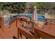 A wood back deck features a dining set and a grill, and overlooks a large backyard pool surrounded by mature trees at 802 Sugar Creek Se Dr, Conyers, GA 30094