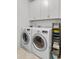 Functional laundry room with white appliances, storage shelves, and overhead cabinets at 2120 Sonoma Se Dr, Smyrna, GA 30080