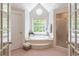Bright bathroom featuring a soaking tub, glass shower, and octagonal window overlooking nature at 3590 Lester Sw Ct, Lilburn, GA 30047
