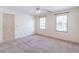 Bright bedroom featuring neutral carpeting, two windows providing plenty of natural light, and ceiling fan at 3590 Lester Sw Ct, Lilburn, GA 30047