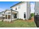 View of the home's back exterior with a covered porch, manicured lawn, and privacy fence in the backyard at 636 Silva St, Cumming, GA 30040