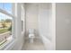 Bright bathroom featuring a toilet, bathtub with white tile surround, and a window offering natural light at 636 Silva St, Cumming, GA 30040
