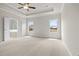 Spacious carpeted bedroom with tray ceilings, windows, and an open door to the ensuite bathroom at 636 Silva St, Cumming, GA 30040