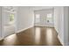 Bright bedroom featuring hardwood floors, natural light from two windows, and an open doorway to an adjacent room at 636 Silva St, Cumming, GA 30040