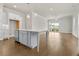 Open-concept kitchen featuring white cabinets, an island with seating, stainless steel appliances, and hardwood floors at 636 Silva St, Cumming, GA 30040