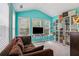 Sitting area with teal accent wall, a comfortable sofa, display shelves, and natural light from large windows at 1186 Arbor Park Sw Ln, Atlanta, GA 30311