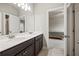 Bathroom featuring double sinks, dark wood cabinets, and an open doorway to a carpeted bedroom at 4720 Gablestone Xing, Hoschton, GA 30548