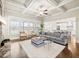 Bright living room features a stone fireplace, coffered ceilings, and open access to the modern kitchen at 4720 Gablestone Xing, Hoschton, GA 30548