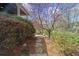 Stone path leads to outdoor fireplace, flowering trees, and manicured bushes at 9860 Coleman Rd, Roswell, GA 30075