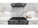 White kitchen with stainless steel range, hood vent, and marble backsplash at 9860 Coleman Rd, Roswell, GA 30075