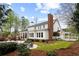 Spacious backyard with a large patio, outdoor fireplace, lush greenery, and a manicured lawn at 12680 Old Surrey Pl, Roswell, GA 30075