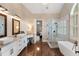 Luxurious bathroom featuring double sinks, a vanity, a shower, and a freestanding tub at 12680 Old Surrey Pl, Roswell, GA 30075