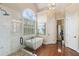Modern bathroom with a freestanding tub, glass-enclosed shower, and hardwood floors at 12680 Old Surrey Pl, Roswell, GA 30075