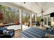 Inviting covered patio with comfortable seating, ceiling fan, outdoor fireplace, and a view of the wooded backyard at 12680 Old Surrey Pl, Roswell, GA 30075
