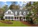 Charming two-story home with a welcoming front porch and meticulously landscaped front yard and shuttered windows at 12680 Old Surrey Pl, Roswell, GA 30075