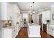 Updated kitchen features white cabinets, stainless appliances, marble countertops, and island with pendant lights at 12680 Old Surrey Pl, Roswell, GA 30075