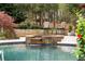 Relaxing pool area featuring a stone-accented waterfall spa, plenty of seating, and a private backyard setting at 12680 Old Surrey Pl, Roswell, GA 30075