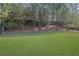 Expansive backyard featuring a lush green lawn, mature trees, and a retaining wall at 3740 Williams Point Dr, Cumming, GA 30028