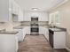 Well-lit kitchen features granite countertops, stainless steel appliances, and classic white cabinets at 10164 Sunny Sw Dr, Covington, GA 30014