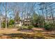 Large, lush backyard featuring mature trees and a partial view of the home's back facade and screened-in porch at 2025 Fairway Crossing Dr, Woodstock, GA 30188