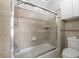 Bathroom features shower-tub combo with glass doors, toilet, and tiled walls at 2025 Fairway Crossing Dr, Woodstock, GA 30188