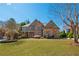 Beautiful brick home featuring lush green lawn, mature trees, and lovely landscaping at 2025 Fairway Crossing Dr, Woodstock, GA 30188