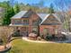 Beautiful two-story brick home with a manicured front lawn and mature trees at 2025 Fairway Crossing Dr, Woodstock, GA 30188