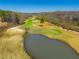 Scenic aerial view showcasing a verdant golf course, pond, mature trees, and clear blue sky at 2025 Fairway Crossing Dr, Woodstock, GA 30188