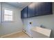 Functional laundry room with basin sink, upper cabinets, and window at 2025 Fairway Crossing Dr, Woodstock, GA 30188