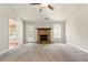 Bright living room with a ceiling fan, stone fireplace, and carpet flooring with access to the kitchen at 1715 Eden Valley Ct, Loganville, GA 30052