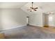 Open living room featuring carpet flooring, vaulted ceiling, a ceiling fan, and an entryway to the kitchen at 1715 Eden Valley Ct, Loganville, GA 30052