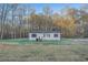 Single-story home surrounded by trees and an ample front yard with a trashcan on the side at 355 Double D Rd, Temple, GA 30179