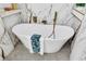 Elegant freestanding bathtub with gold fixtures set against marble-tiled walls and mosaic tile flooring at 3637 Elm St, Atlanta, GA 30354