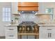 Close-up of a kitchen range with stainless steel oven, gold hardware, white cabinets, and stylish backsplash at 3637 Elm St, Atlanta, GA 30354