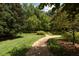 Serene backyard featuring a gravel path, lush lawn, and mature trees providing shade and privacy for outdoor enjoyment at 2440 Peachtree Nw Rd # 1, Atlanta, GA 30305