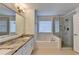 Bright bathroom featuring double sinks, a tub, and a glass shower at 3550 Lakeheath Dr, Cumming, GA 30041