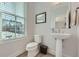 This powder room features a pedestal sink, stylish fixtures, and a view to the outdoors at 6187 Kelly Carlin Way, Norcross, GA 30071