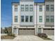 Modern townhome featuring a gray and white exterior, brick accents, a two-car garage, and professional landscaping at 6187 Kelly Carlin Way, Norcross, GA 30071