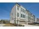 Stylish townhouse showcasing a gray and white facade, complemented by brick details, a garage, and lush landscaping at 6187 Kelly Carlin Way, Norcross, GA 30071