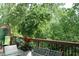 A relaxing outdoor space with a glass table, chairs, and lush greenery with trees visible from the wooden deck at 2022 Raven Way, Atlanta, GA 30341
