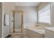 Bright main bathroom features a walk-in shower, a soaking tub, a large window, and neutral decor at 1030 Blankets Creek Dr, Canton, GA 30114