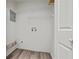 Bright laundry room with wood-look flooring, shelving, and a utility sink hookup, freshly painted walls at 9023 Stoneleigh Trce, Douglasville, GA 30134