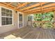 Cozy covered porch with natural wood floors, string lights, and view to backyard at 189 Meadow Spring Dr, Temple, GA 30179