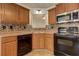 Kitchen with black appliances, wood cabinets, and corner sink at 189 Meadow Spring Dr, Temple, GA 30179
