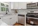 Bright kitchen with white cabinets, stainless steel appliances, stylish faucet, and marble backsplash at 1703 Derrill Dr, Decatur, GA 30032